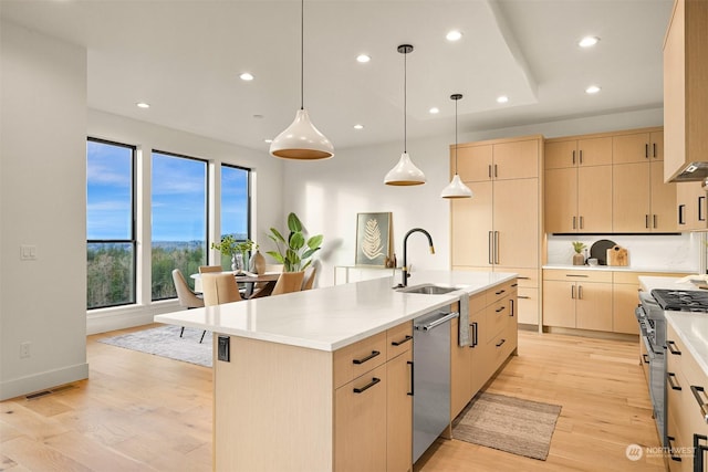 kitchen featuring appliances with stainless steel finishes, sink, a center island with sink, and light brown cabinetry