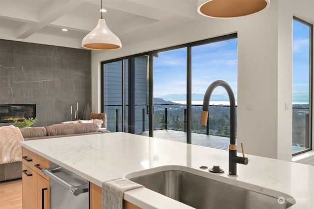 kitchen featuring pendant lighting, sink, coffered ceiling, light stone countertops, and a mountain view