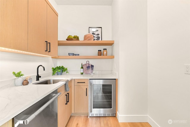 bar featuring sink, light stone countertops, stainless steel dishwasher, beverage cooler, and light brown cabinets