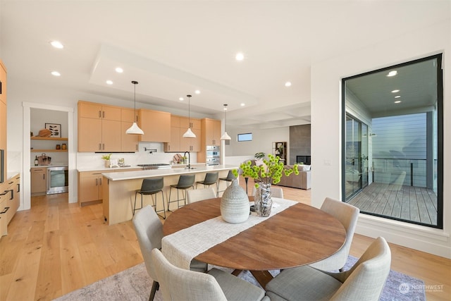 dining room featuring sink, light hardwood / wood-style flooring, and beverage cooler