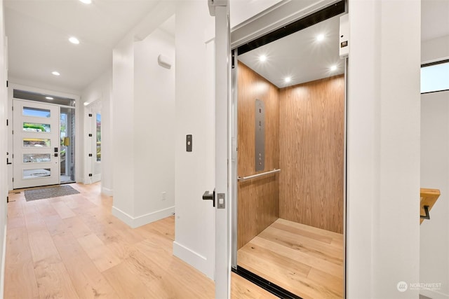 hall featuring elevator and light hardwood / wood-style flooring