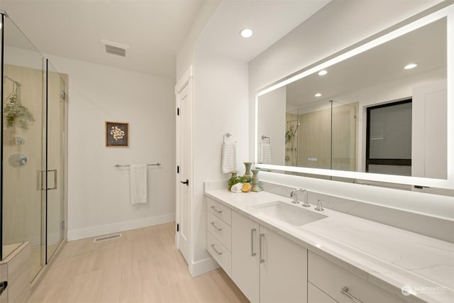 bathroom featuring a shower with door and vanity