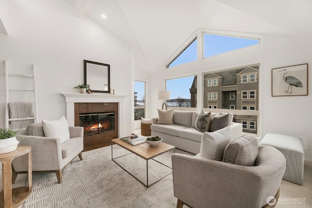 living area with high vaulted ceiling, a tiled fireplace, and recessed lighting