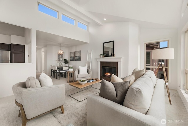 living room featuring recessed lighting, high vaulted ceiling, a glass covered fireplace, and light colored carpet