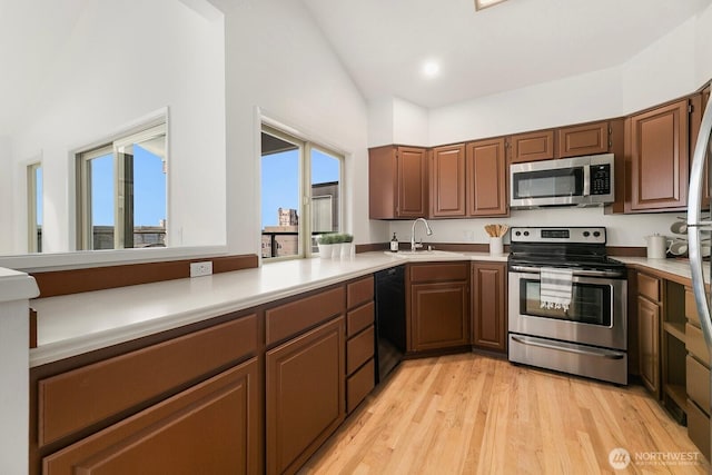 kitchen with appliances with stainless steel finishes, light countertops, light wood-style floors, a sink, and recessed lighting