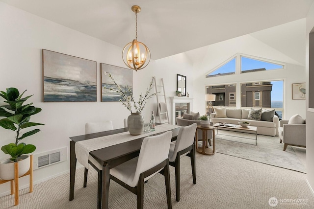 dining area featuring visible vents, a glass covered fireplace, an inviting chandelier, carpet, and vaulted ceiling