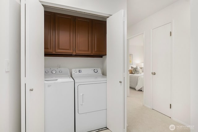 laundry room with washing machine and clothes dryer, cabinet space, and light colored carpet