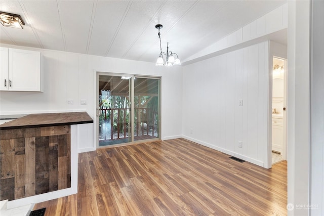 unfurnished dining area with lofted ceiling, dark hardwood / wood-style floors, and a chandelier