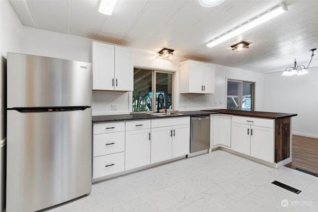 kitchen featuring appliances with stainless steel finishes, sink, white cabinets, and kitchen peninsula