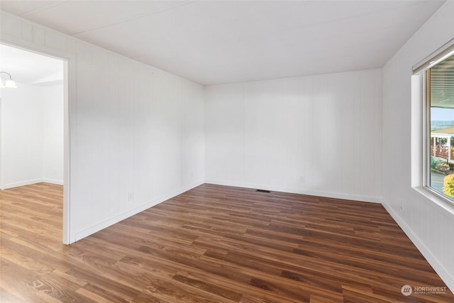 empty room featuring dark wood-type flooring and a chandelier