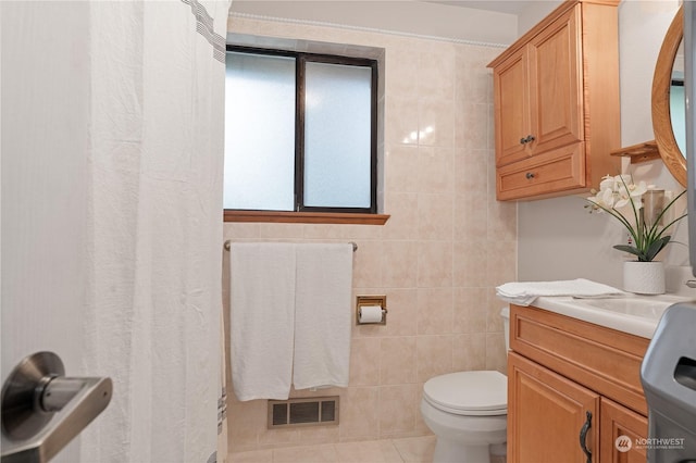 bathroom featuring vanity, tile patterned floors, tile walls, and toilet