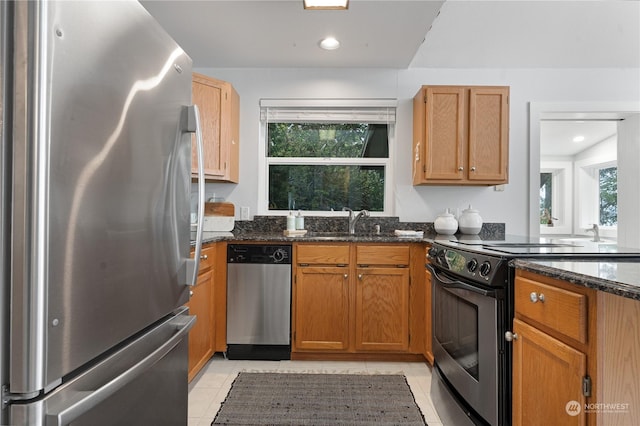 kitchen with light tile patterned flooring, appliances with stainless steel finishes, sink, and dark stone counters