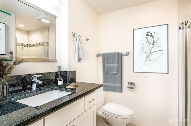 bathroom featuring a shower with door, vanity, and toilet