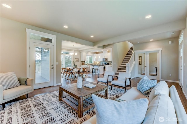 living area with light wood finished floors, baseboards, a chandelier, stairway, and recessed lighting