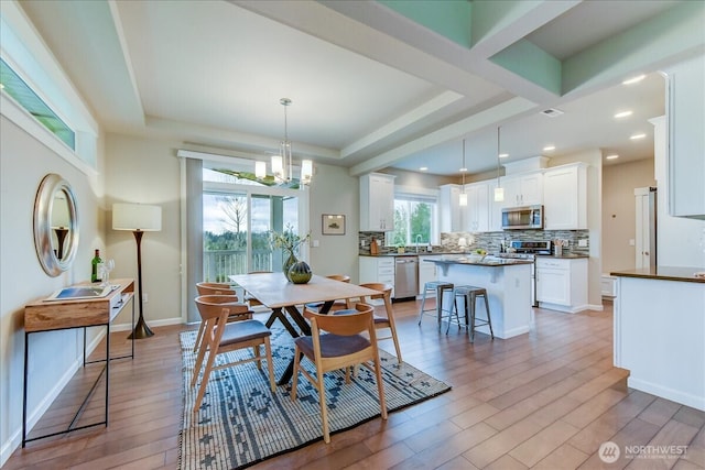 dining area featuring baseboards, a tray ceiling, recessed lighting, light wood-style flooring, and an inviting chandelier