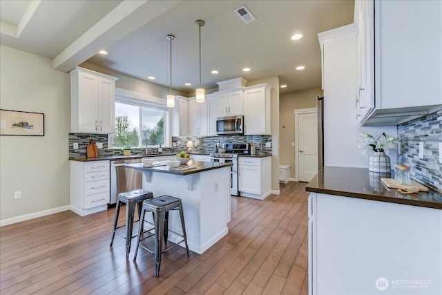 kitchen with white cabinetry, dark countertops, a breakfast bar area, and stainless steel appliances