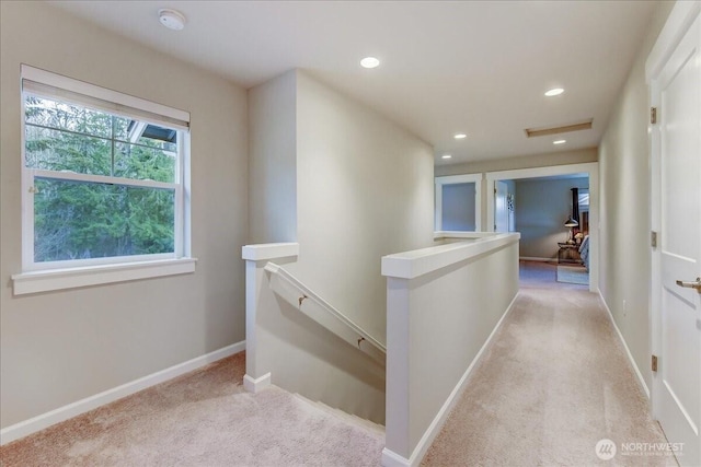 hallway with an upstairs landing, recessed lighting, light colored carpet, and baseboards