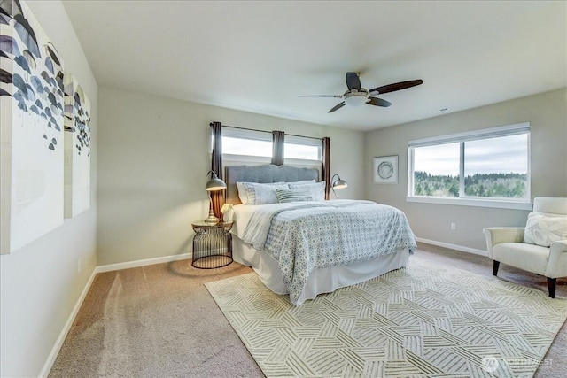 bedroom with light carpet, multiple windows, a ceiling fan, and baseboards