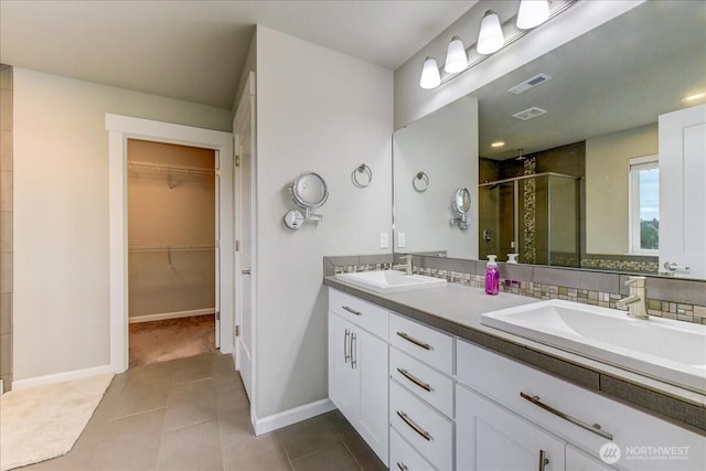 bathroom featuring double vanity, visible vents, a stall shower, and a sink