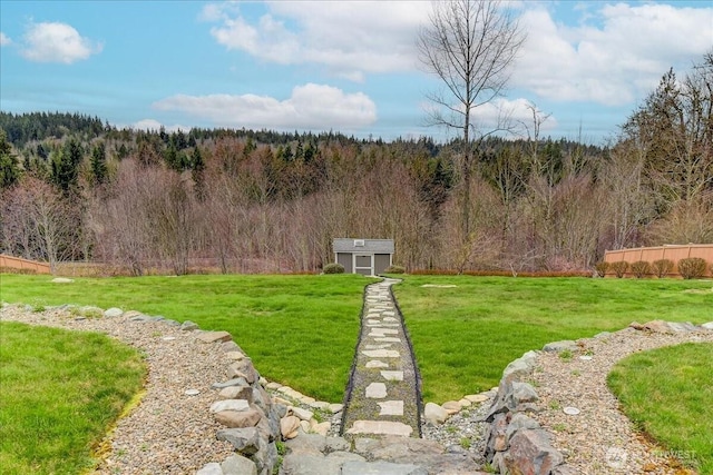 view of yard with a storage unit, a forest view, and an outdoor structure