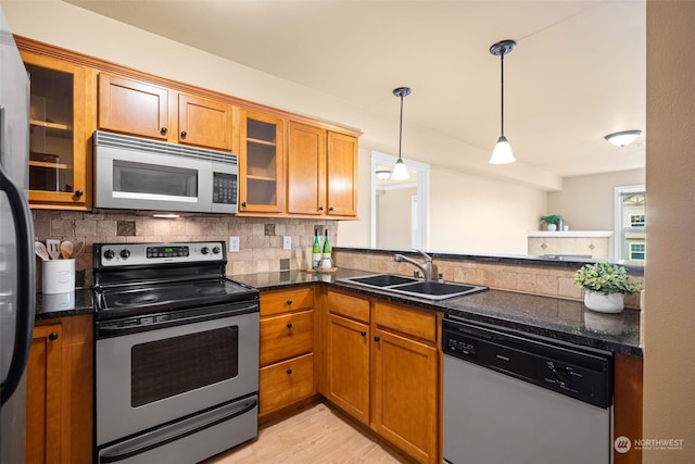 kitchen with sink, decorative light fixtures, dark stone countertops, appliances with stainless steel finishes, and decorative backsplash