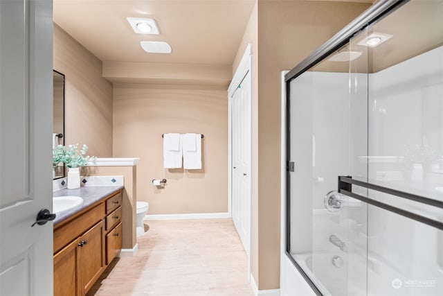 full bathroom featuring enclosed tub / shower combo, vanity, hardwood / wood-style flooring, and toilet