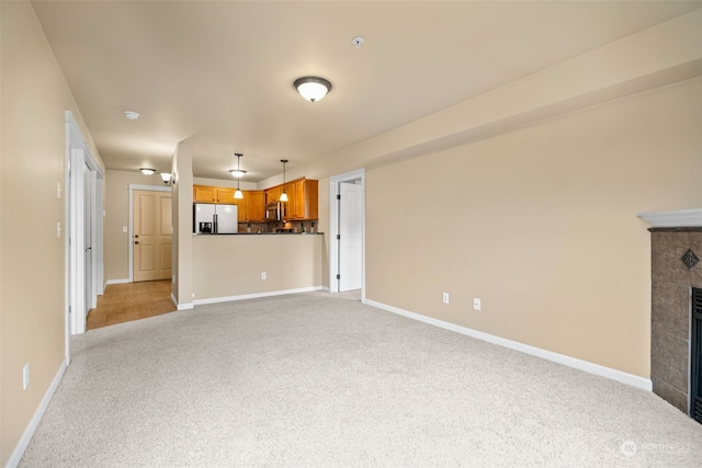 unfurnished living room featuring light carpet and a fireplace