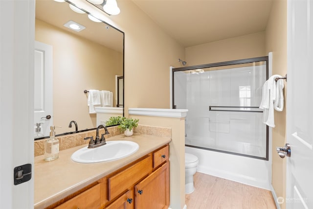 full bathroom with toilet, vanity, shower / bath combination with glass door, and hardwood / wood-style floors