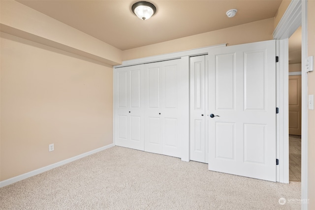 unfurnished bedroom featuring light carpet and a closet