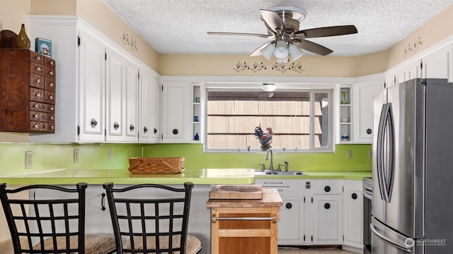 kitchen featuring a breakfast bar, sink, a textured ceiling, stainless steel appliances, and white cabinets