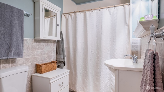 bathroom with vanity, tile walls, and toilet