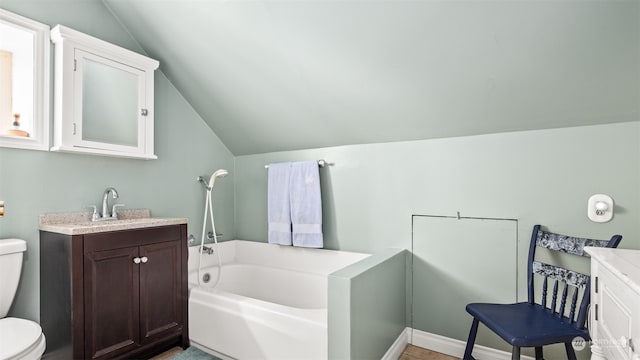 bathroom with a tub to relax in, vanity, toilet, and vaulted ceiling