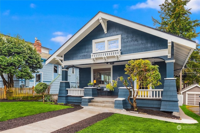 view of front facade with a porch, an outdoor structure, a front yard, and a garage