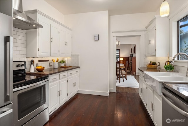 kitchen featuring dark wood-type flooring, sink, wall chimney range hood, stainless steel appliances, and white cabinets