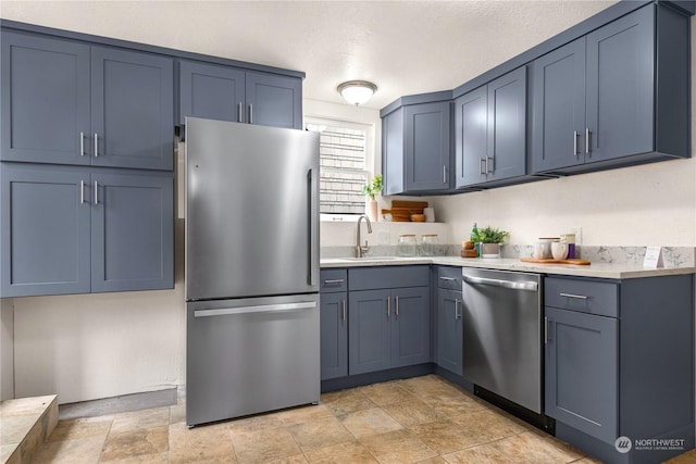 kitchen featuring appliances with stainless steel finishes, sink, and blue cabinetry