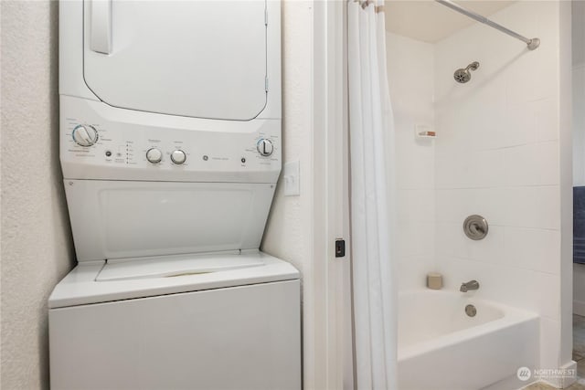 bathroom with stacked washing maching and dryer and tiled shower / bath combo