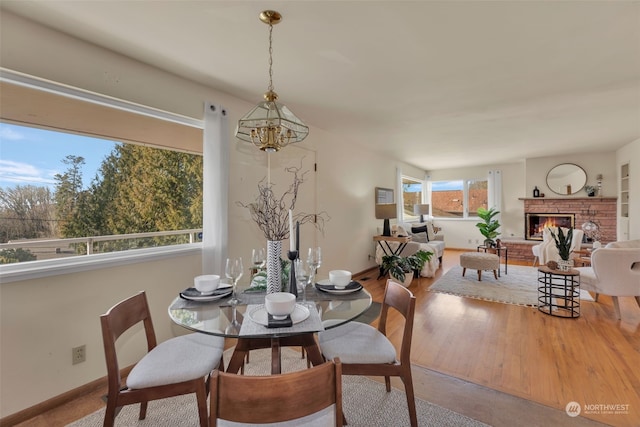 dining room featuring hardwood / wood-style flooring and a brick fireplace