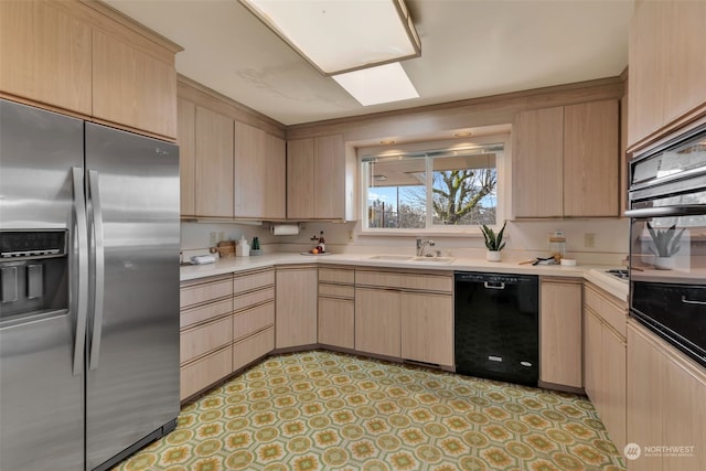 kitchen featuring light brown cabinetry, a skylight, dishwasher, sink, and stainless steel fridge with ice dispenser