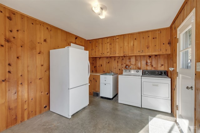 laundry room featuring separate washer and dryer, wooden walls, and cabinets