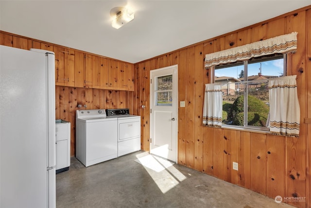 washroom featuring wooden walls, cabinets, and washing machine and clothes dryer