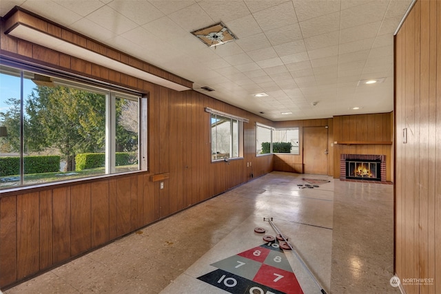 unfurnished living room with a brick fireplace and wooden walls