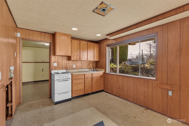 kitchen featuring sink, electric range, and wood walls