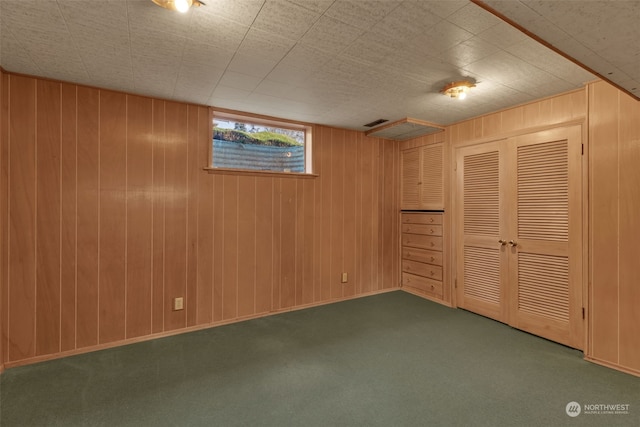 basement with wood walls and dark colored carpet