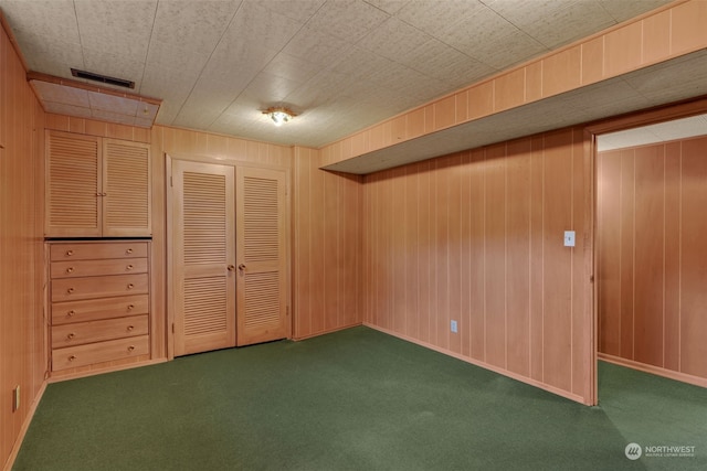 basement featuring wood walls and dark colored carpet