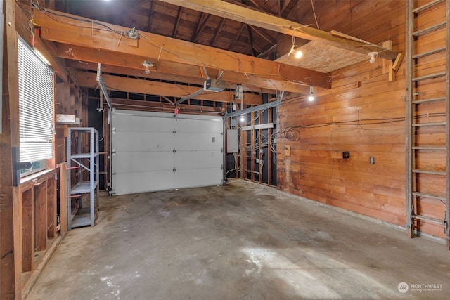 garage with a garage door opener, electric panel, and wood walls