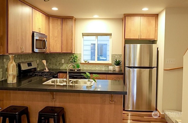 kitchen featuring a kitchen bar, sink, kitchen peninsula, and appliances with stainless steel finishes