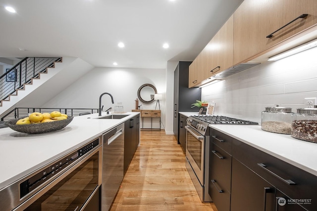 kitchen featuring sink, tasteful backsplash, light hardwood / wood-style flooring, light brown cabinets, and appliances with stainless steel finishes