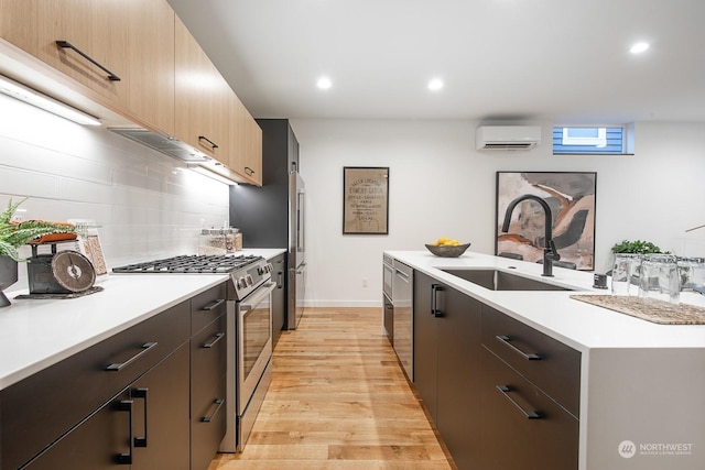 kitchen featuring sink, a wall mounted AC, backsplash, stainless steel appliances, and light hardwood / wood-style flooring