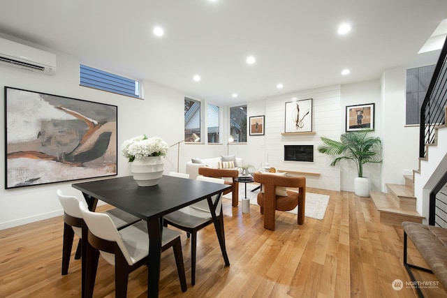 dining space featuring a wall mounted AC and light wood-type flooring