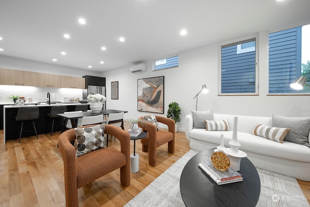 living room with a wall mounted air conditioner and light hardwood / wood-style flooring